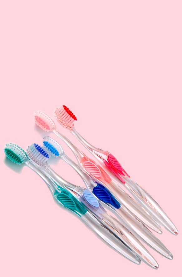 Adult toothbrushes in a pile on a vertical pink background.